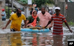 An elderly Sri Lankan woman is pulled on a makeshift raft at a flooded area in Colombo, Sri Lanka, May 17, 2016.