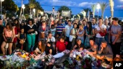 People gather at a makeshift memorial to honor the victims of an attack, near the area where a truck mowed through revelers in Nice, France, July 15, 2016. 