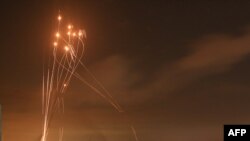 Cohetes iluminan el cielo nocturno mientras son disparados hacia Israel desde Beit Lahia en el norte de la Franja de Gaza el 14 de mayo de 2021.