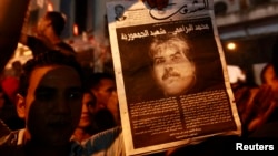 示威者手持遇刺身亡的布拉赫米的头像。2013年7月25日