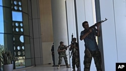 Rebel fighters take shelter as an intense gunbattle erupted outside the Corinthia hotel, where many foreign journalists are staying, in Tripoli, Libya, August 25, 2011