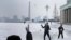 Niños norcoreanos juegan con nieve en la Plaza Kim Il Sung, en Pyongyang, el domingo 16 de diciembre de 2018, al inicio de la temporada invernal, al fondo la Torre 'The Juche Idea'.