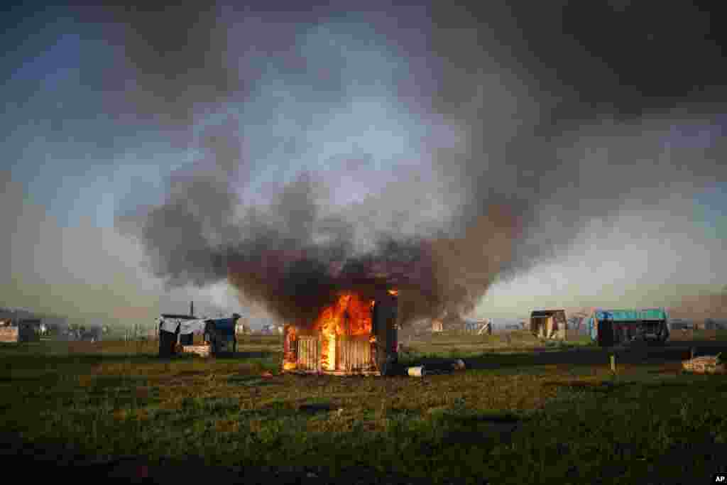 A home burns as people are removed from a squatters camp by police in Guernica, Buenos Aires province, Argentina. Evicted families say they have nowhere to go as the COVID-19 pandemic continues.