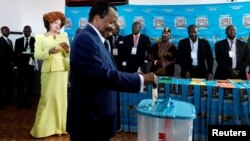 Le président camerounais Paul Biya dépose son bulletin de vote auprès de son épouse Chantal Biya lors de l'élection présidentielle à Yaoundé, au Cameroun, le 7 octobre 2018.