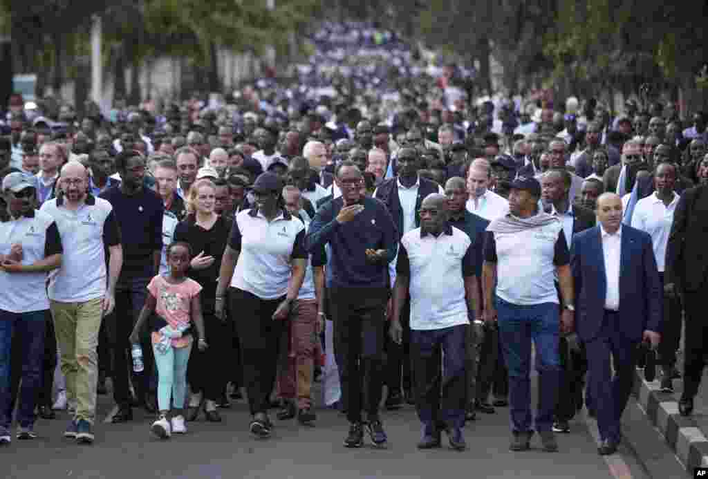 Rwanda's President Paul Kagame, center, gestures as he and first lady Jeannette Kagame, center-left, lead a "Walk to Remember" accompanied by Ethiopia's Prime Minister Abiy Ahmed, far left, Prime Minister of Belgium Charles Michel, second left, France's Herve Berville, third left, and Governor General of Canada Julie Payette, fourth left, from the parliament building to Amahoro stadium in downtown Kigali, April 7, 2019.