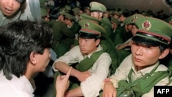 FILE - A dissident Chinese student speaks to soldiers as crowds gather in central Beijing on June 3, 1989.