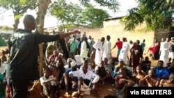 A police officer talks to people sitting on the ground after being freed by police from an Islamic rehabilitation center, in Ibadan, Nigeria, in this picture released by Nigeria Police, Nov. 5, 2019.