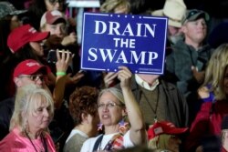 FILE - A supporter holds up a "Drain the Swamp" sign before U.S. President Donald Trump arrives to speak at a "Make America Great Again" rally in Washington, Michigan, April 28, 2018. The "Drain the Swamp" motto" dates back to Trump's 2016 campaign.