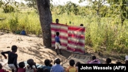 Des enfants regardent un spectacle de marionnettes qui vise à guérir les enfants déplacés qui ont été témoins d'atrocités dans le nord du Mozambique, dans un camp de déplacés à Metuge le 21 mai 2021.