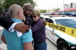 Terry DeCarlo, Direktur LGBT Center di Orlando, Florida, Kelvin Cobaris, pastur Impact Church, tengah, dan Komisaris kota Patty Sheehan berpelukan setelah penembakan di Orlando, Florida.