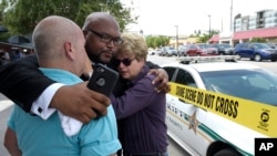 Terry DeCarlo, executive director of the LGBT Center of Central Florida, left, Kelvin Cobaris, pastor of The Impact Church, center, and Orlando City Commissioner Patty Sheehan console each other after a shooting at a nightclub in Orlando, Fla., June 12, 2016.