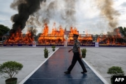 FILE - A police officer walks in front of a burning pile of seized illegal drugs during a destruction ceremony to mark the United Nations' "International Day against Drug Abuse and Illicit Trafficking" in Yangon on June 26, 2020. (Photo by Sai Aung Main/AFP)
