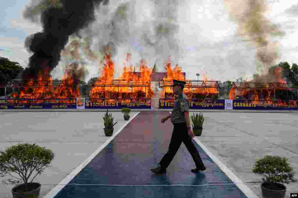 A police officer walks in front of a fire burning seized illegal drugs during a ceremony to mark the United Nations&#39; International Day Against Drug Abuse and Illicit Trafficking in Yangon, Myanmar.