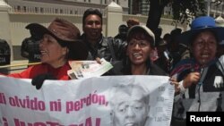 ARCHIVO - Manifestantes sostienen un cartel contra el expresidente Sánchez de Lozada en una protesta en La Paz, Bolivia, 2012.