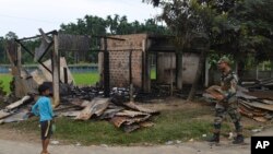 FILE - A paramilitary soldier patrols past a shop that was set on fire in Rowa village, about 220 kilometers from Agartala, in the northeastern Indian state of Tripura, Oct. 27 2021.