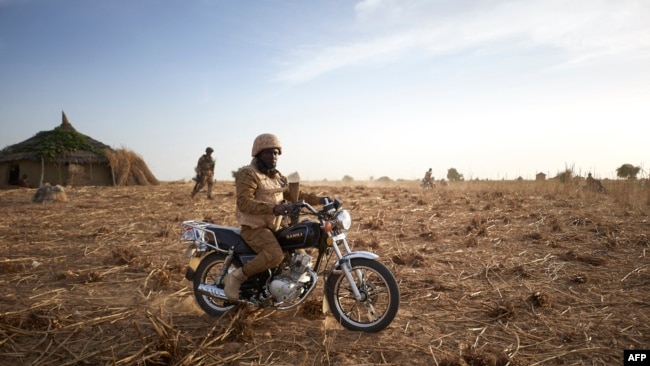 FILE - A soldier of the Burkina Faso Army sits on his motorcycle during a patrol in Burkina Faso, November 9, 2019. Two soldiers were killed by a homemade bomb in southeast Burkina Faso on October 11, 2021.