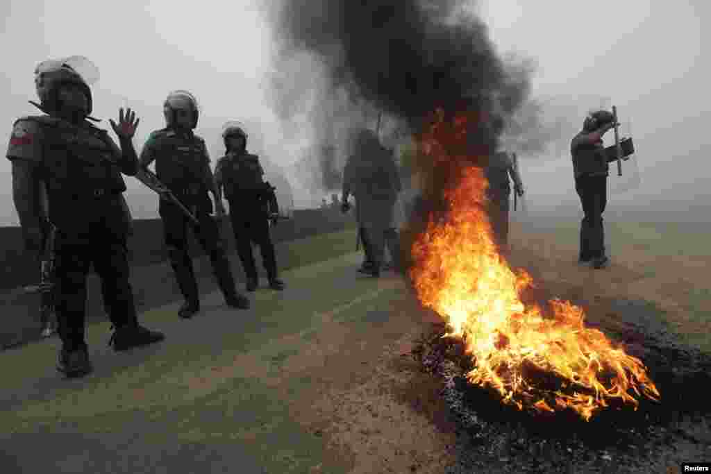 Police stand guard near tyres that activists of the Bangladesh Nationalist Party (BNP) set on fire during a nationwide blockade in Dhaka December 9, 2012. Police fired rubber bullets and tear gas to disperse protesters staging blockades across Bangladesh 