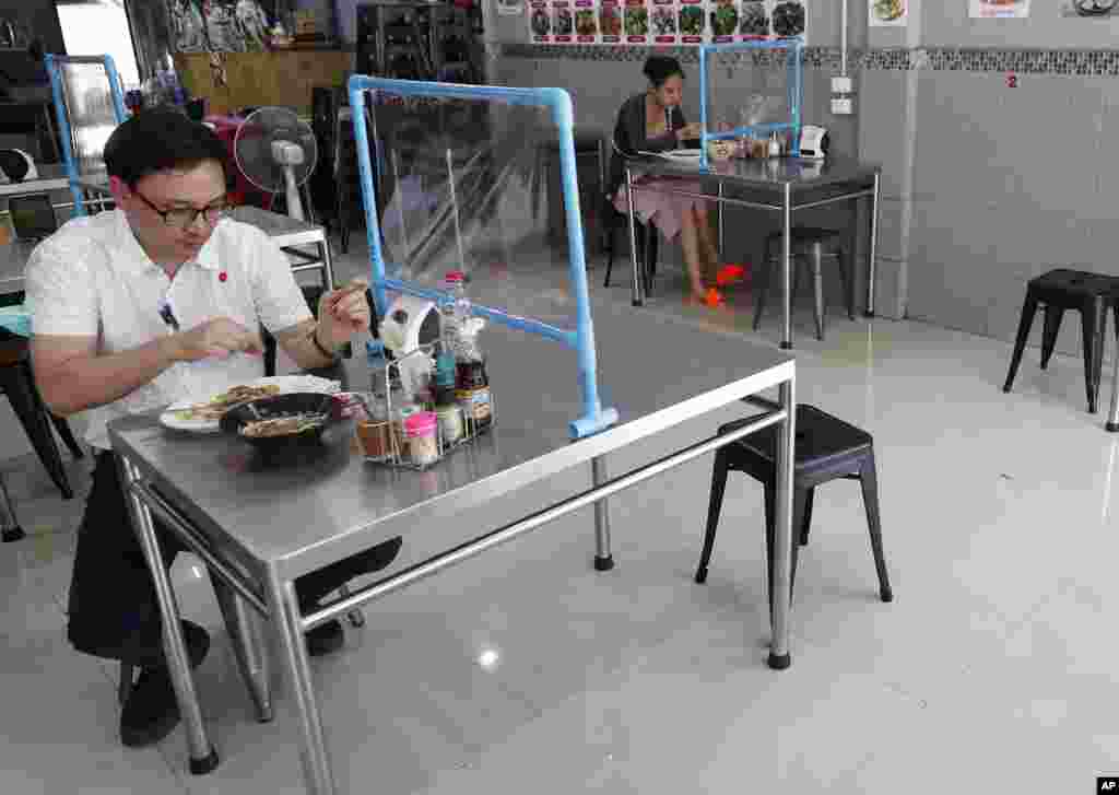 Customers eat lunch behind plastic shields to help curb the spread of the coronavirus in Bangkok, Thailand, Tuesday, May 5, 2020. (AP Photo/Sakchai Lalit)