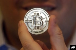 FILE - Mike Caldwell, a 35-year-old software engineer, holds a 25 Bitcoin token at his shop in Sandy, Utah.