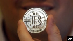 FILE - Mike Caldwell, a 35-year-old software engineer, holds a 25 Bitcoin token at his shop in Sandy, Utah. 