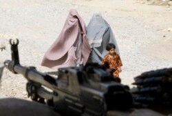 Perempuan Afghanistan berpakaian burqa dan seorang gadis berjalan melewati kantor polisi setempat di kota Kandahar, Afghanistan selatan, 22 Maret 2010. (REUTERS/Shamil Zhumatov)