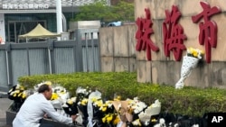 A man offers flowers outside the Zhuhai People's Fitness Plaza where a man rammed his car into people exercising at the sports center, in Zhuhai in southern China's Guangdong province on Nov. 13, 2024.