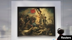 Une femme admire le tableau d'Eugène Delacroix, 'La Liberté guidant le peuple' (28 juillet 1830), à la Galerie du Temps au musée du Louvre-Lens dans le nord de la France, le 3 décembre 2012.