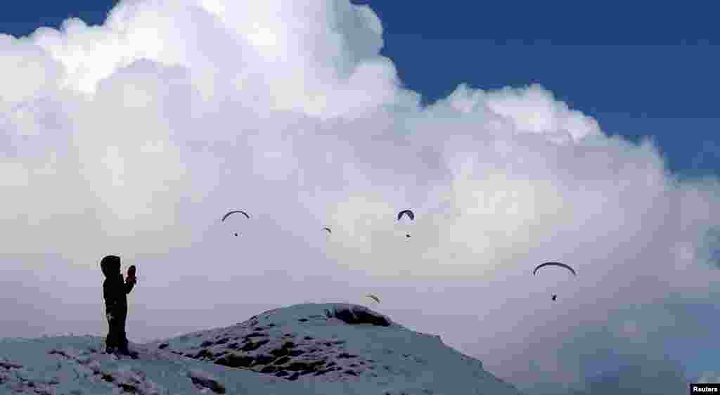 A child watches people paragliding on the hill of Mam Tor near the village of Castleton, Derbyshire, Britain.