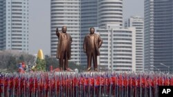 Sinh viên mang quốc kỳ và hai tượng đồng của lãnh đạo quá cố Kim Il Sung và Kim Jong Il trong cuộc diễu hành tại Bình Nhưỡng hôm 15/4