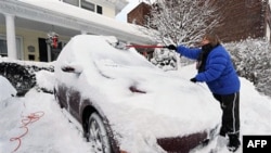 A woman shovels snow off her car in a driveway that was knee-deep in snow in Port Washington, New York, Jan 27 2011