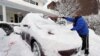 A woman shovels snow off her car in a driveway that was knee-deep in snow in Port Washington, New York, Jan 27 2011