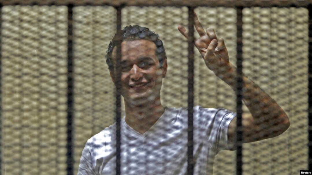 FILE - Egyptian activist Ahmed Douma gestures from behind bars at the New Cairo court, on the outskirts of Cairo.