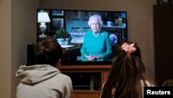 Noah y Milly, dos niños de Hertford, Gran Bretaña, de 9 y 7 años, escuchan el discurso a la nación de la reina Isabel, a raíz de la pandemia de la COVID-19, la enfermedad producida por el coronavirus. Abril 5 de 2020.