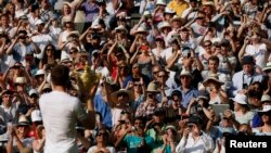 Andy Murray of Britain holds the winners trophy up to the spectators after defeating Novak Djokovic of Serbia in their men's singles final tennis match at the Wimbledon Tennis Championships, in London Jul. 7, 2013.