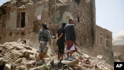 People stand amid the rubble of a house damaged by Saudi-led airstrike in the old city of Sana'a, Yemen, Sept. 19, 2015.