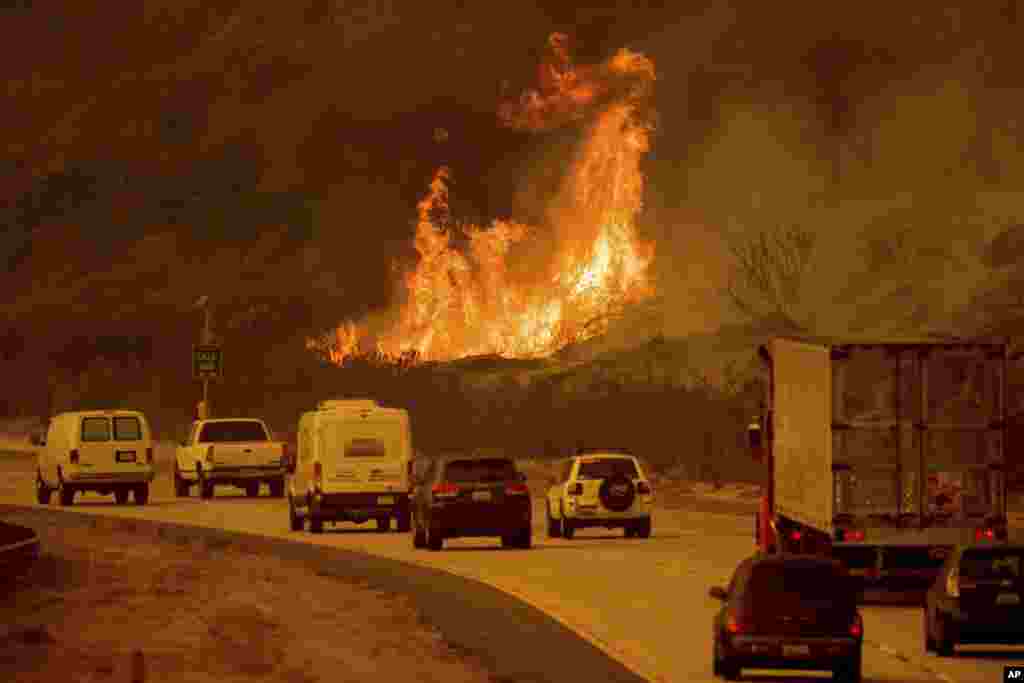 Flames from a wildfire leap above traffic on Highway 101 north of Ventura, California, Dec. 6, 2017.