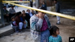 Una mujer y su hija observan a los investigadores trabajar en la escena de un crimen en el que un hombre fue asesinado a tiros en la ciudad de Guatemala, el 7 de febrero de 2012.