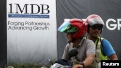 FILE - Motorcyclists pass a 1Malaysia Development Berhad (1MDB) billboard at the Tun Razak Exchange development in Kuala Lumpur, Malaysia, Feb. 3, 2016.