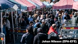 People walk at a market as the City of Malmo has placed fences and information to reduce congestion at the stands, due to the coronavirus pandemic, in Malmoe, Sweden, 25 April 2020.