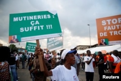 A partisan of the ruling party RDR (Rally of the republicans) holds a placard during a rally against the mutiny close to the military headquarters in Abidjan, Ivory Coast, May 13, 2017. The placard reads, "Mutinies: it's enough."