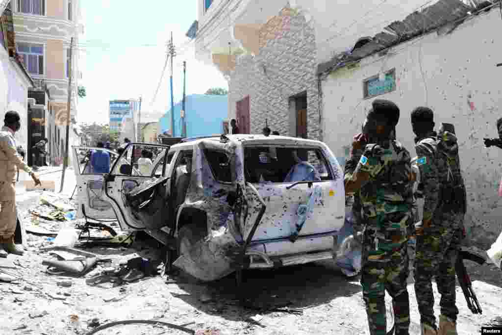 Somali security look at the wreckage of a vehicle at the scene of an explosion Mogadishu. Somalia&#39;s government spokesperson was wounded in the explosion at a road junction set off by a suicide bomber, police and the national news agency said.