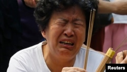 A family member of a passenger aboard the missing Malaysia Airlines flight MH370 cries as she burns incense to pray at Yonghegong Lama Temple in Beijing, June 15, 2014. 