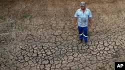 FILE - Riaan du Plessis, a farmer, stands on the cracked earth that three weeks ago was the bottom of a reservoir on his farm in Groot Marico, South Africa, Nov. 12, 2015. Six of South Africa's nine provinces have been hit by drought.