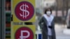 FILE - A woman walks near a money exchange office in Seoul, South Korea, March 8, 2022. 