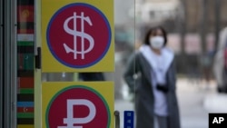 FILE - A woman walks near a money exchange office in Seoul, South Korea, March 8, 2022. 