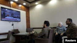 Men watch the elections to choose the new interim government on a TV screen at a cafe in Benghazi, Libya, Feb., 5, 2021.
