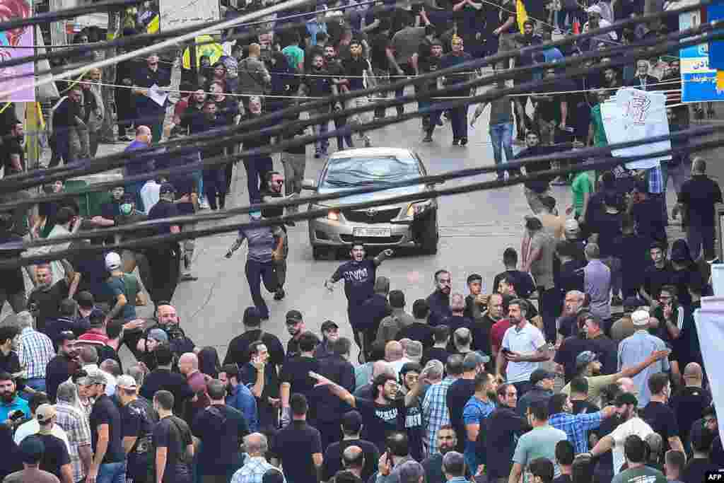 People react around a car after a reported explosion occurred during the funeral of those killed when hundreds of paging devices exploded across Lebanon the previous day, in Beirut&#39;s southern suburbs. A second wave of device explosions killed three people in Hezbollah strongholds of Lebanon on September 18.