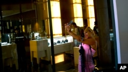 A Cuban girl takes a selfie in front of a window of a luxury store at the Manzana de Gomez Kempinski five-star hotel in Havana, Cuba, Monday, May 8, 2017.
