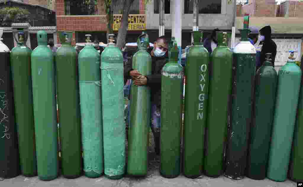 Edgar Barbaran exchanges a small, empty oxygen tank for a large one as he waits since the previous day for a refill shop to open in Callao, Peru, amid the COVID-19 pandemic.