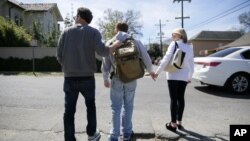 FILE - Parents help their son, Ben, cross a street in New Orleans, Louisiana, March 2, 2016. Ben was diagnosed with autism when he was two and a half years old.